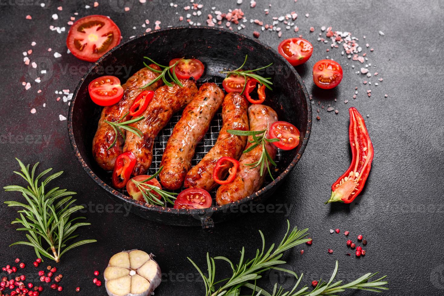 salsicce alla griglia con verdure e spezie su sfondo nero foto