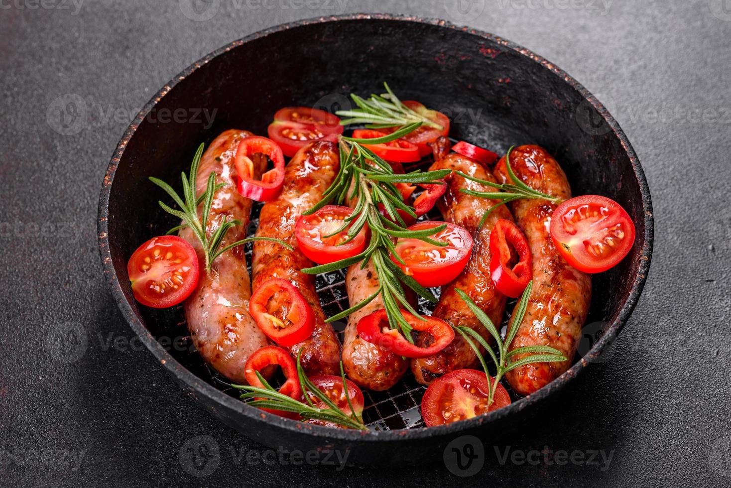 salsicce alla griglia con verdure e spezie su sfondo nero foto