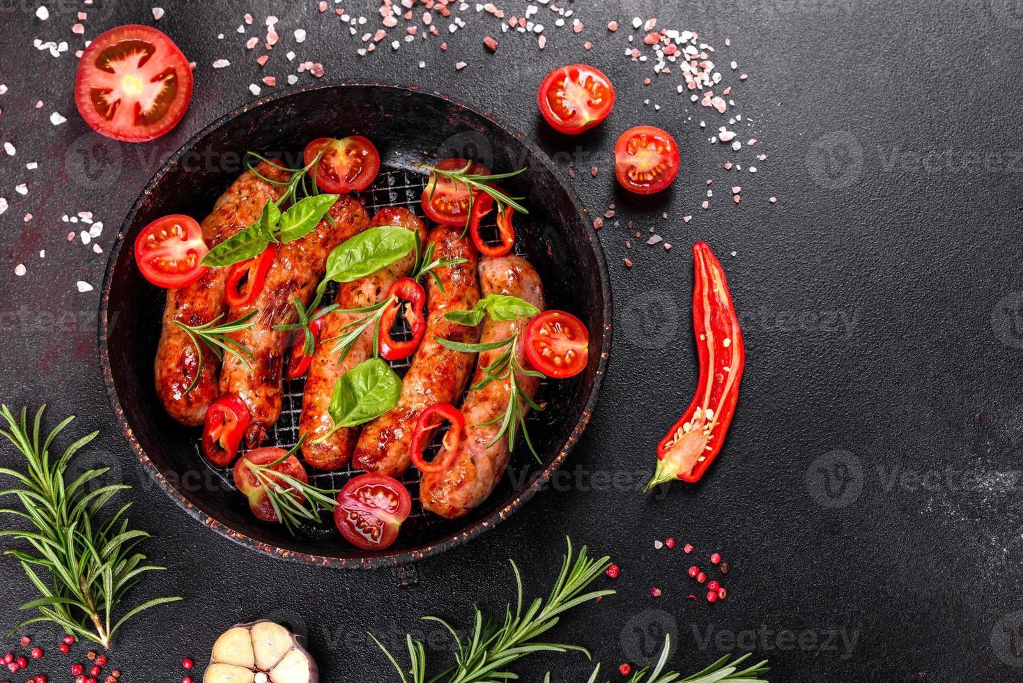 salsicce alla griglia con verdure e spezie su sfondo nero foto