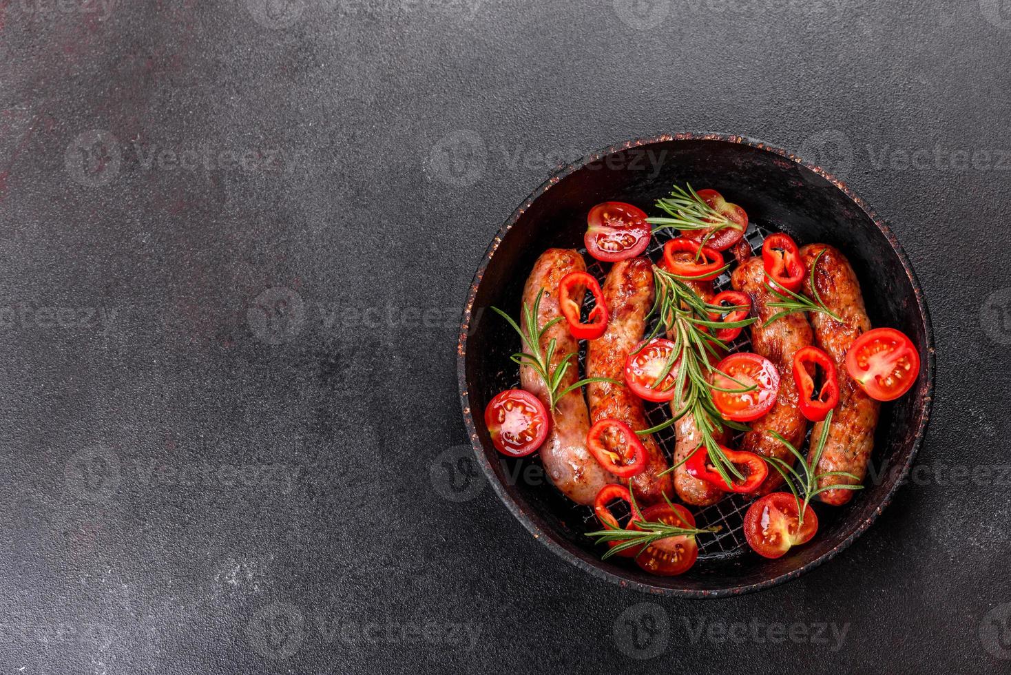salsicce alla griglia con verdure e spezie su sfondo nero foto