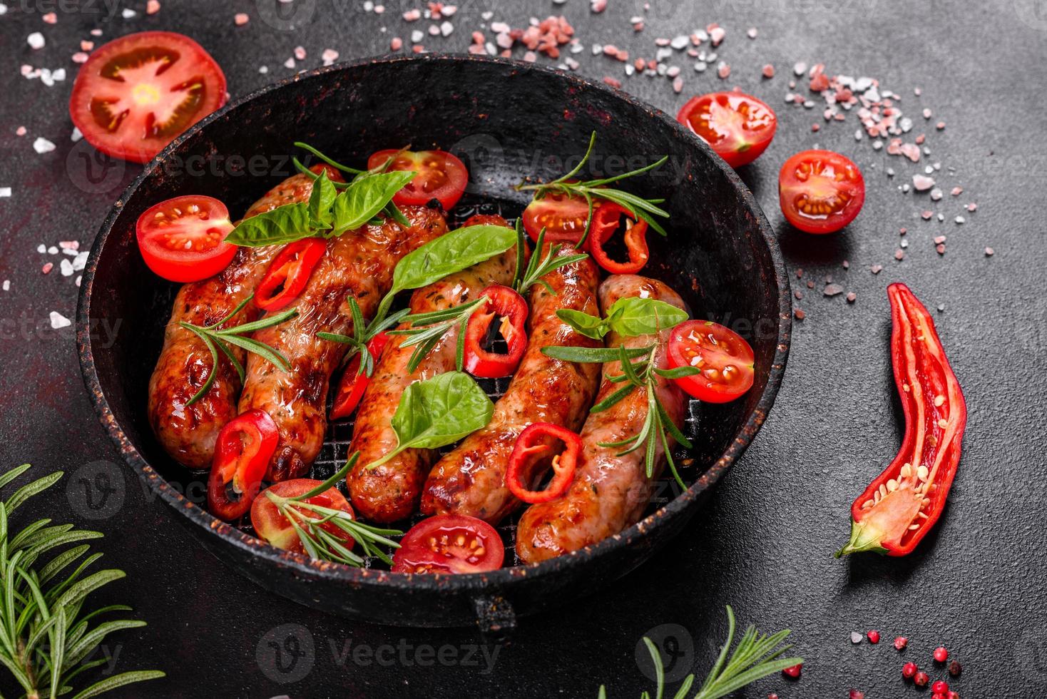 salsicce alla griglia con verdure e spezie su sfondo nero foto