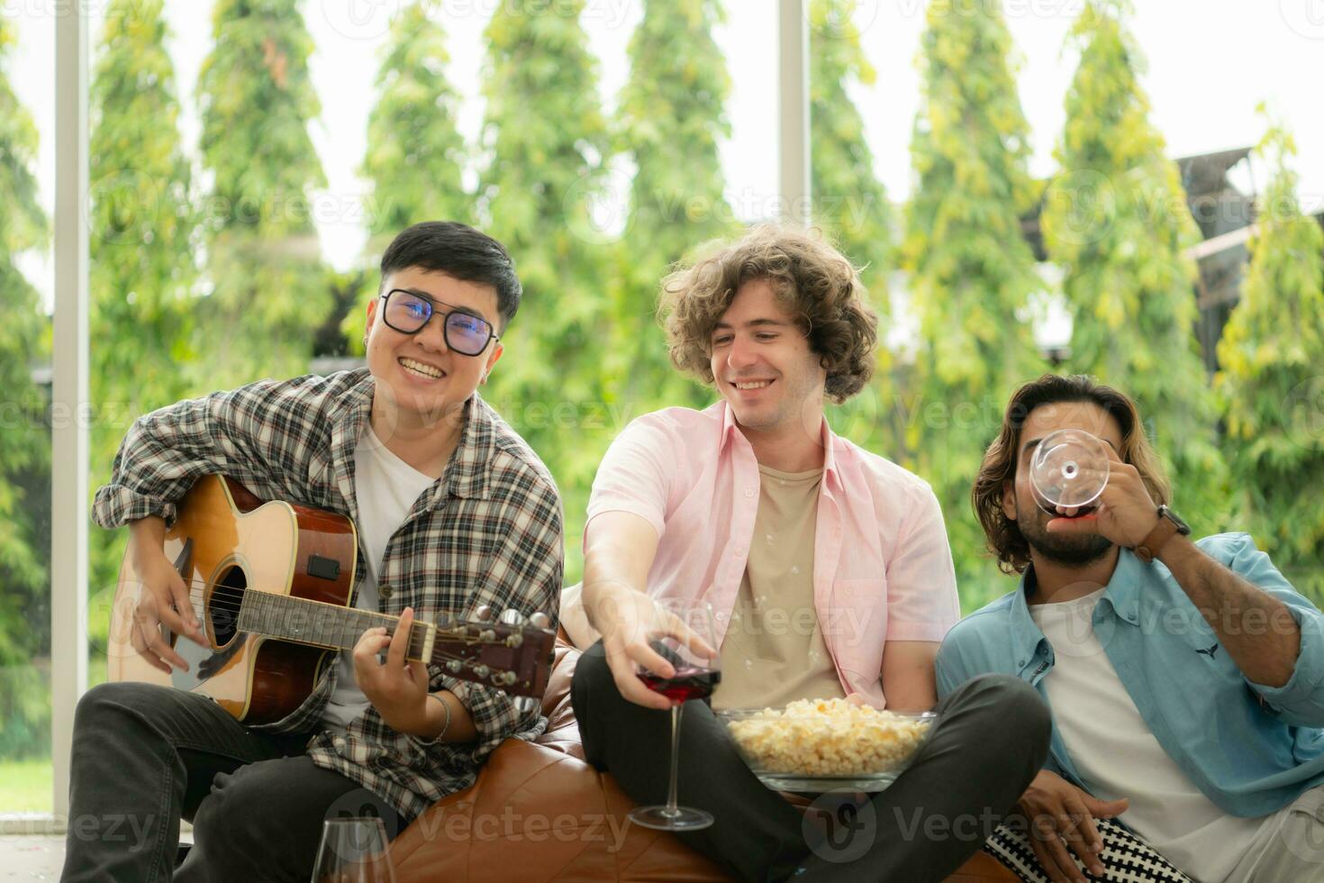 multietnico gruppo di amici avendo divertimento giocando chitarra e cantando insieme a casa foto