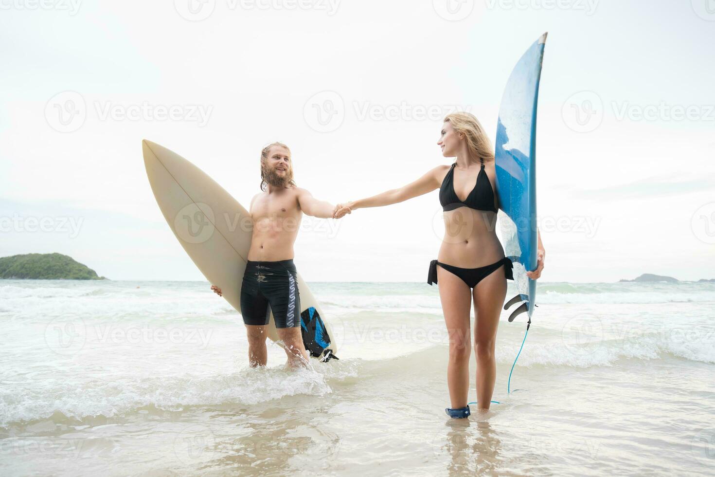 coppia di surfers Tenere mani e guardare a ogni altro su spiaggia foto