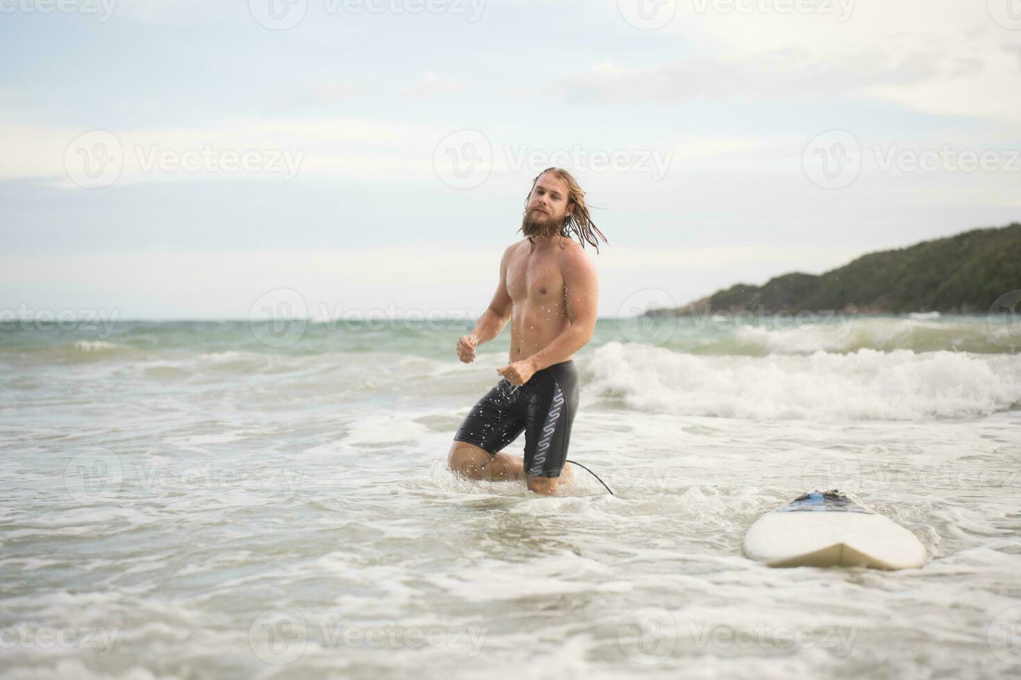 ritratto di un' bello giovane uomo con tavola da surf a il spiaggia foto