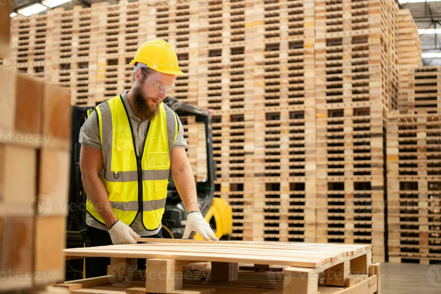 ritratto di giovane maschio falegname Lavorando nel un' la lavorazione del legno fabbrica, lui è indossare un' sicurezza casco e occhiali, controllo il di legno tavole In arrivo su di il legna macinino. foto