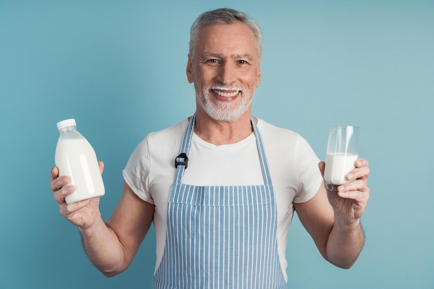 uomo sorridente con in mano un bicchiere di latte e una bottiglia foto