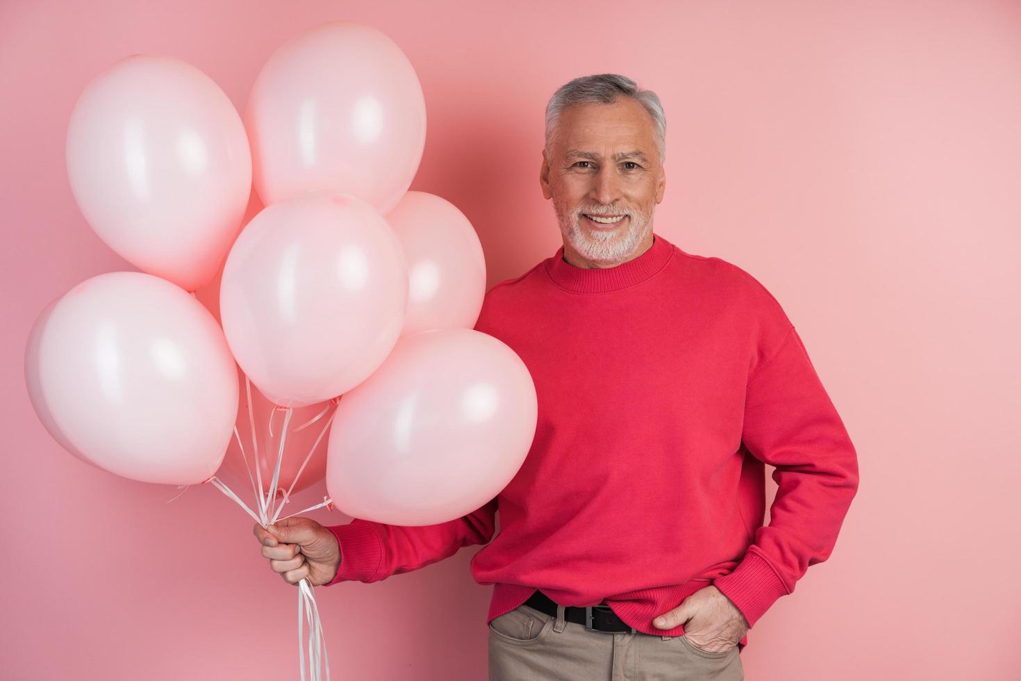 uomo felice che celebra tenendo palloncini rosa foto