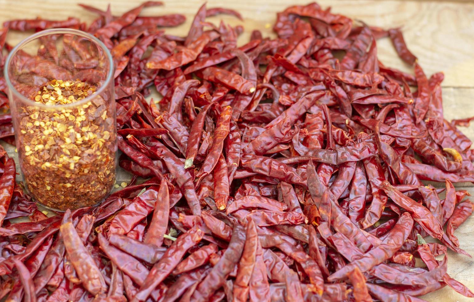 peperoncino essiccato sul tavolo di legno e scaglie di peperoncino in barattolo, spezie foto