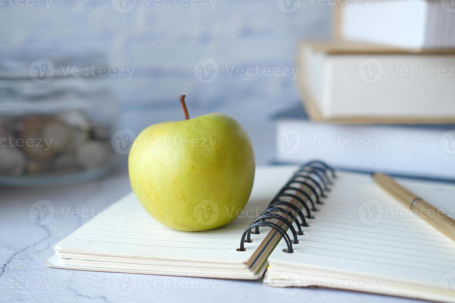 nero al concetto di scuola con mela sul blocco note sul tavolo. foto