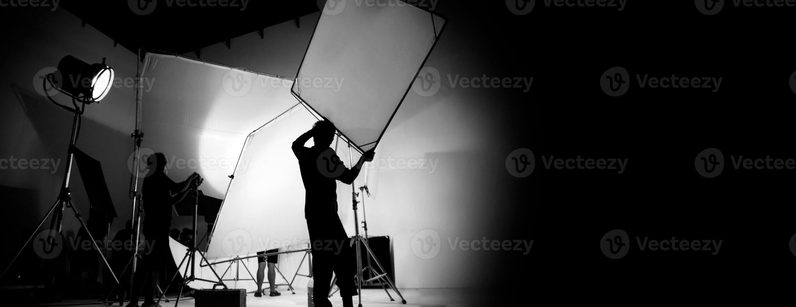 silhouette di video produzione dietro a il scene o B rotolo o fabbricazione di tv commerciale film quello film equipaggio squadra uomo di luce e cineoperatore Lavorando insieme con direttore nel grande studio con professionista attrezzature foto