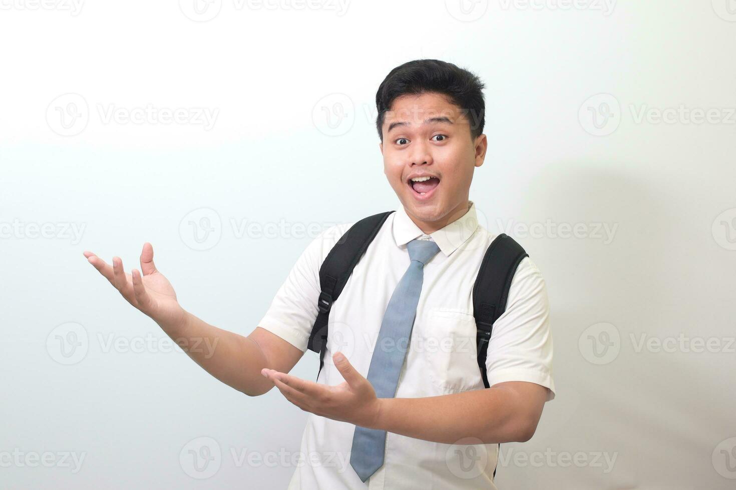 indonesiano anziano alto scuola alunno indossare bianca camicia uniforme con grigio cravatta mostrando Prodotto, puntamento a qualcosa e sorridente. isolato Immagine su bianca sfondo foto