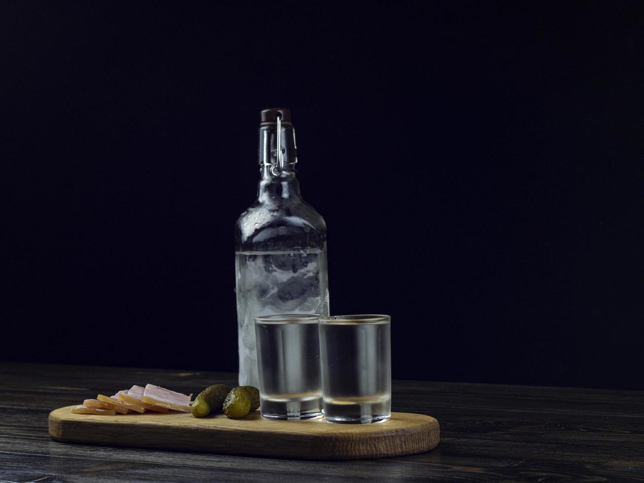 bottiglia di vodka, due bicchieri appannati con vodka fredda foto