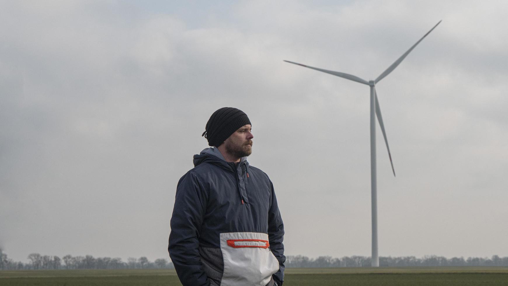 uomo in piedi in un campo sullo sfondo di mulini a vento foto