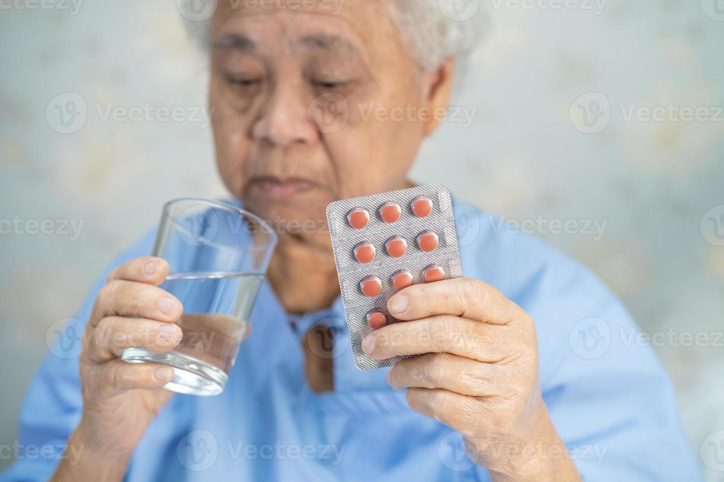 paziente asiatico senior della donna che tiene le pillole della capsula degli antibiotici? foto