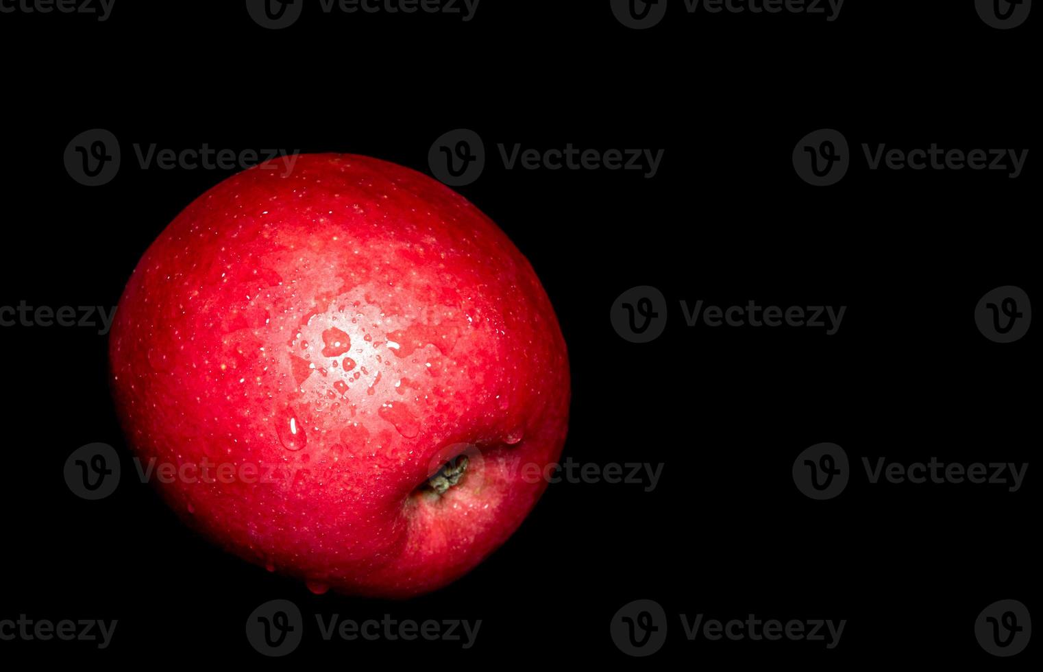 goccia d'acqua sulla superficie lucida della mela rossa su sfondo nero foto