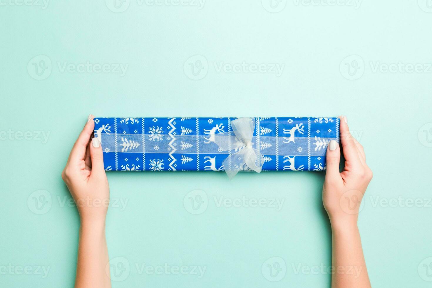 donna mani dare avvolto Natale o altro vacanza fatto a mano presente nel colorato carta. presente scatola, decorazione di regalo su blu tavolo, superiore Visualizza con copia spazio foto