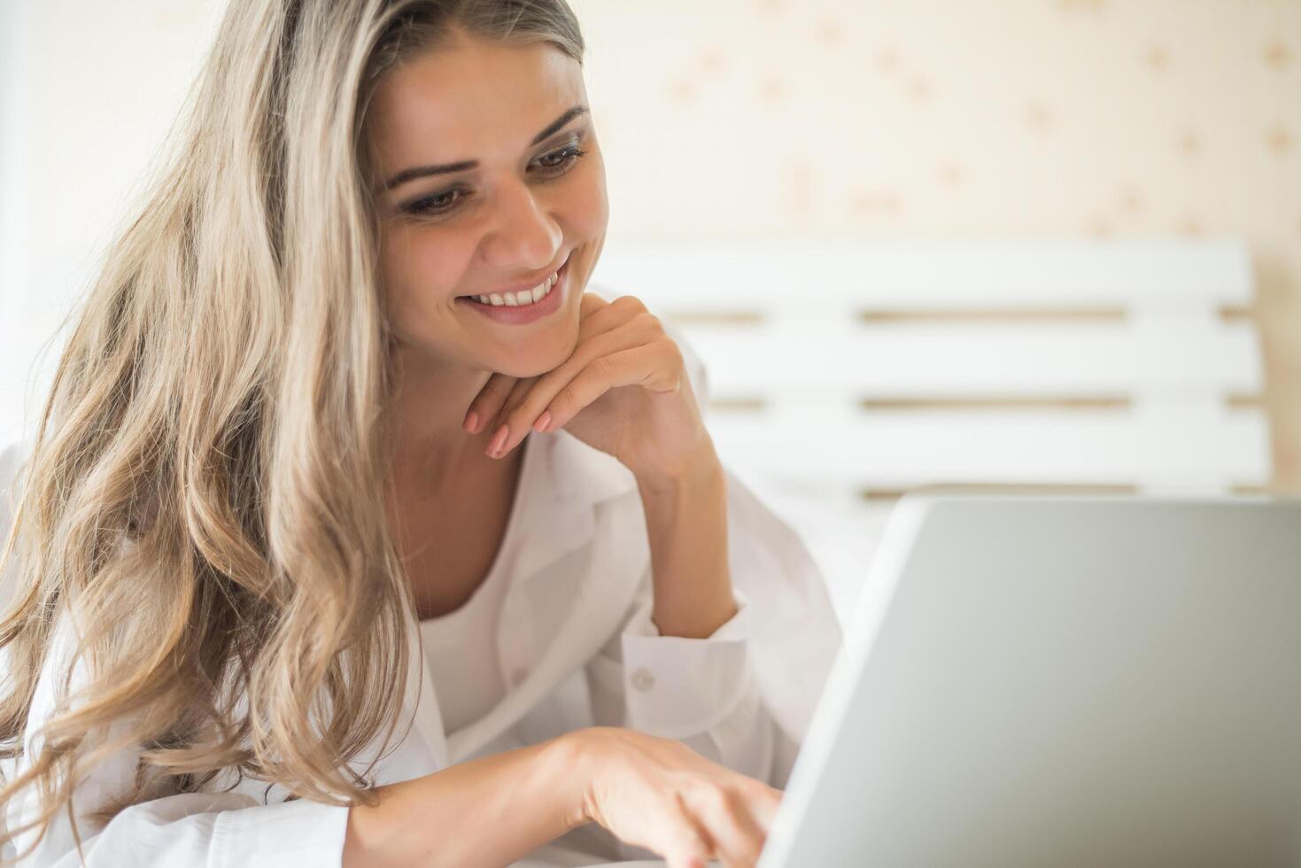 bella donna felice che lavora su un laptop sul letto in casa foto