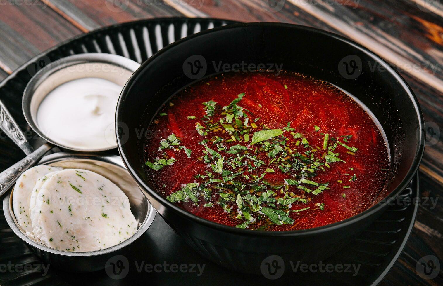 appetitoso piatto borscht servito con pane, lardo affettatrici e acida crema foto