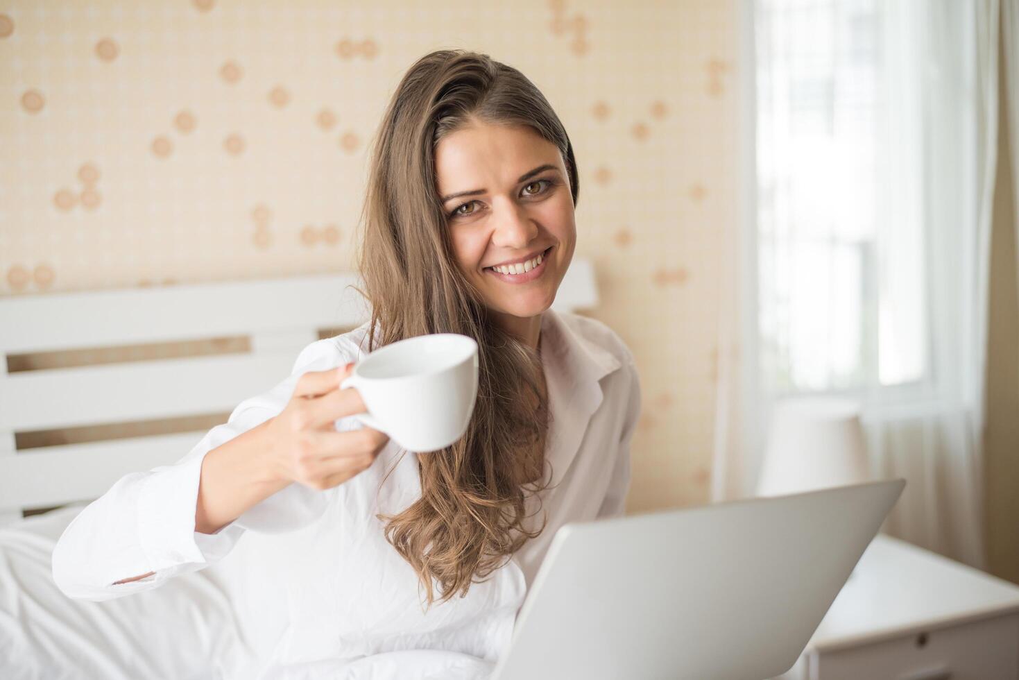 bella donna felice che lavora su un laptop sul letto in casa foto