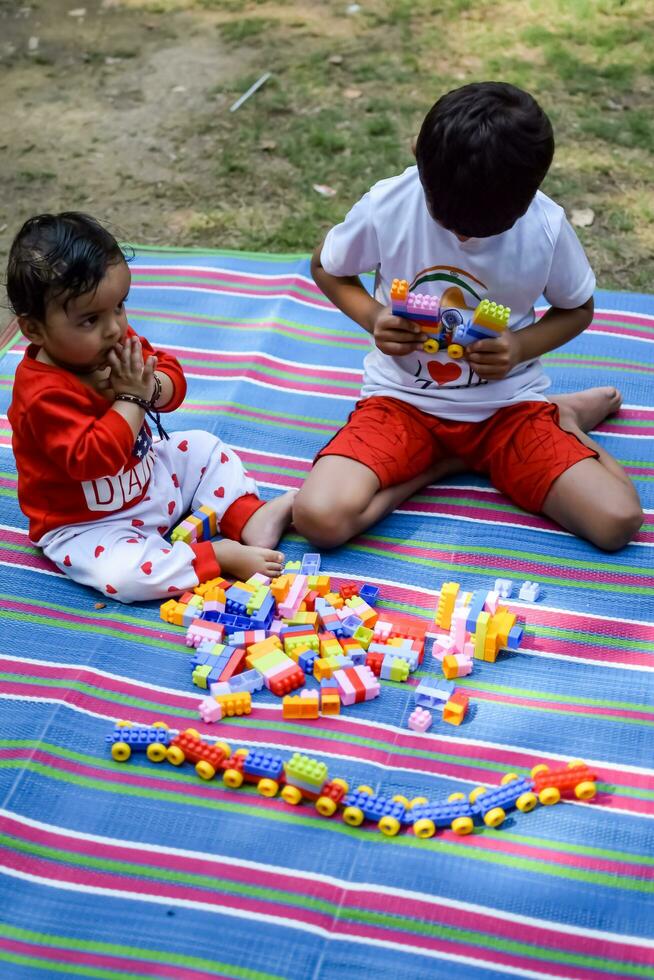 Due contento ragazzi nel società parco, contento asiatico fratelli chi siamo sorridente felicemente insieme. fratelli giocare all'aperto nel estate, migliore gli amici. bambino piccolo bambino ragazzo giocando con il suo contento fratello nel il giardino foto