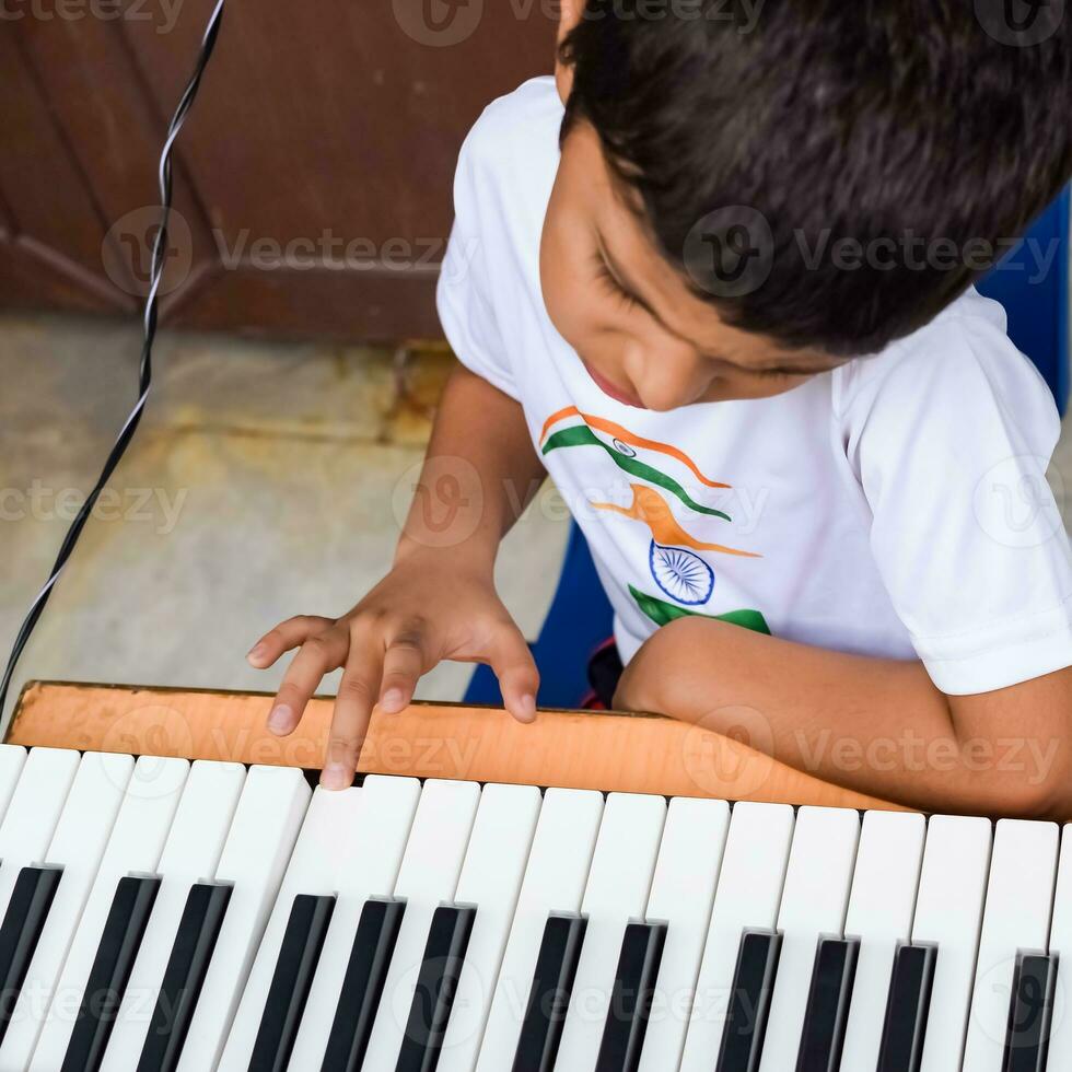 asiatico ragazzo giocando il sintetizzatore o pianoforte. carino poco ragazzo apprendimento Come per giocare pianoforte. del bambino mani su il tastiera interno. foto