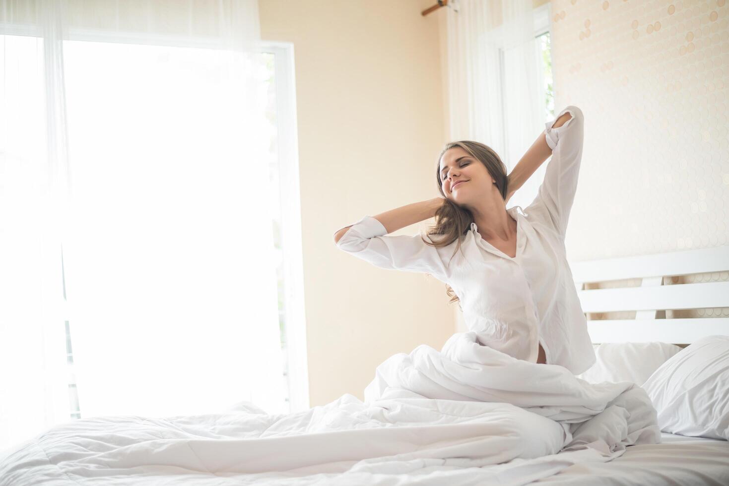 pigra giovane donna seduta in camera da letto foto