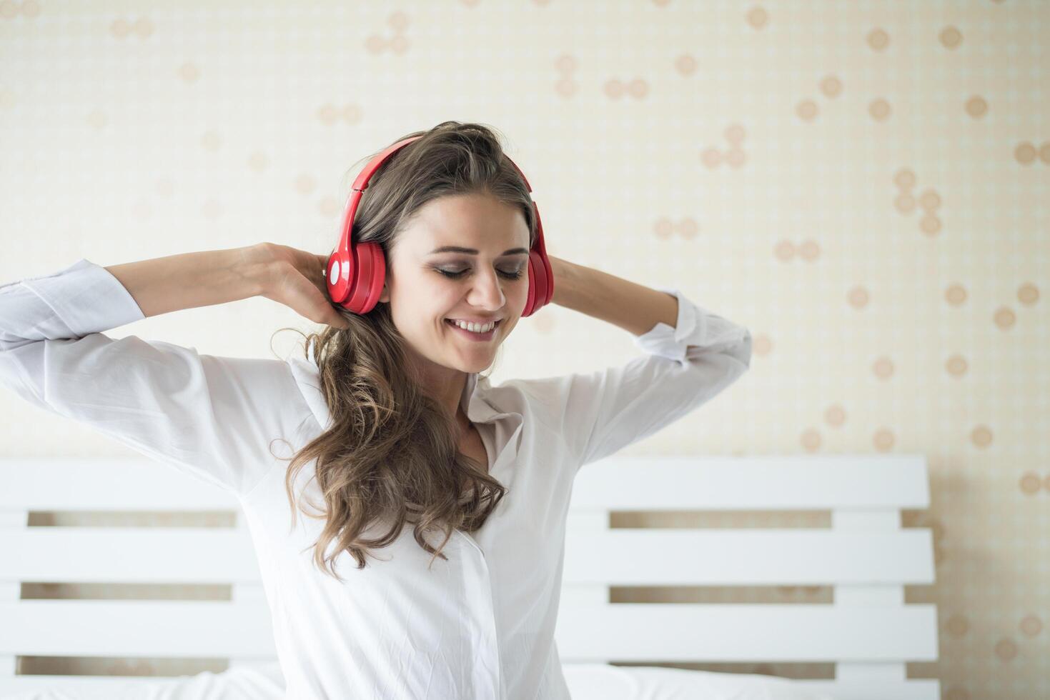 bella donna che ascolta musica al mattino seduta sul letto a casa foto