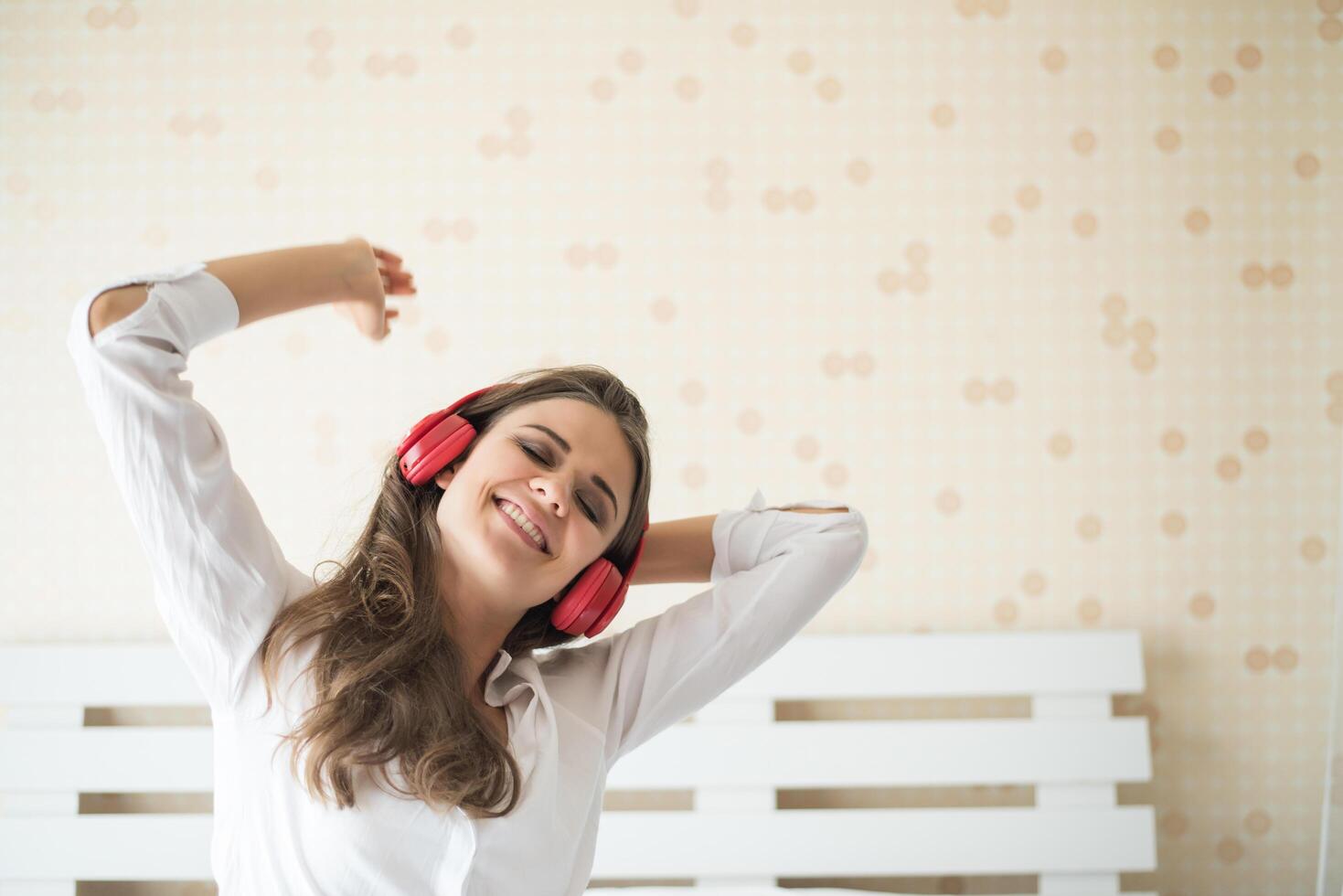 bella donna che ascolta musica al mattino seduta sul letto a casa foto