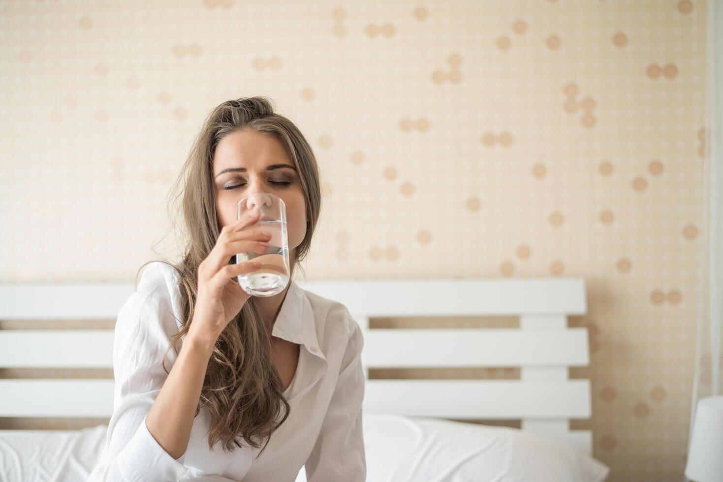 bella donna che beve acqua fresca a letto al mattino foto