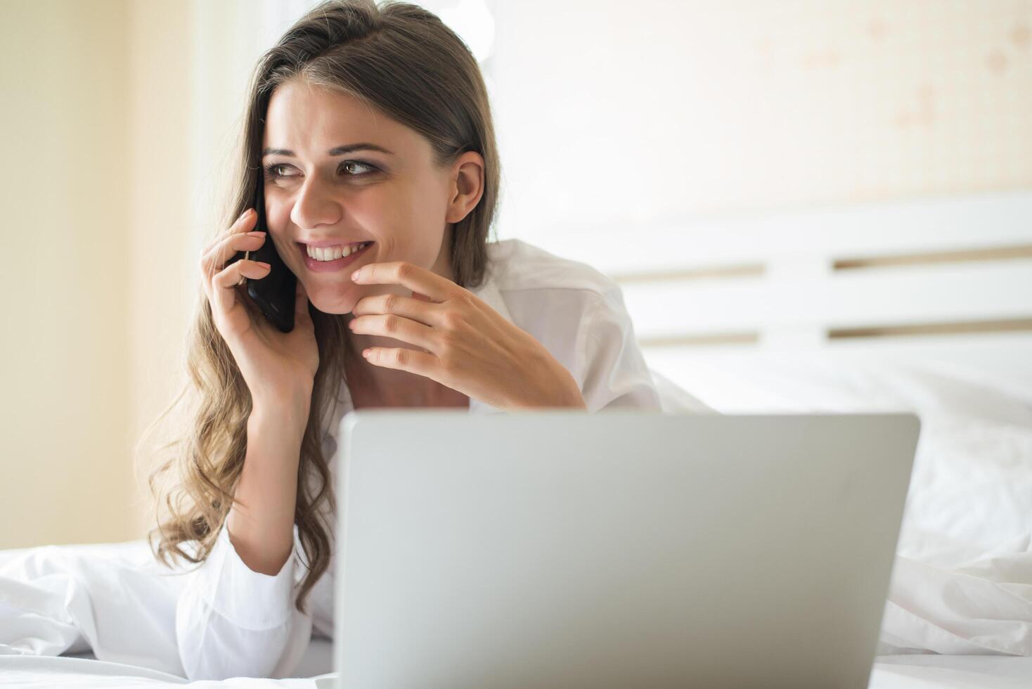 bella donna felice che lavora su un laptop sul letto in casa foto