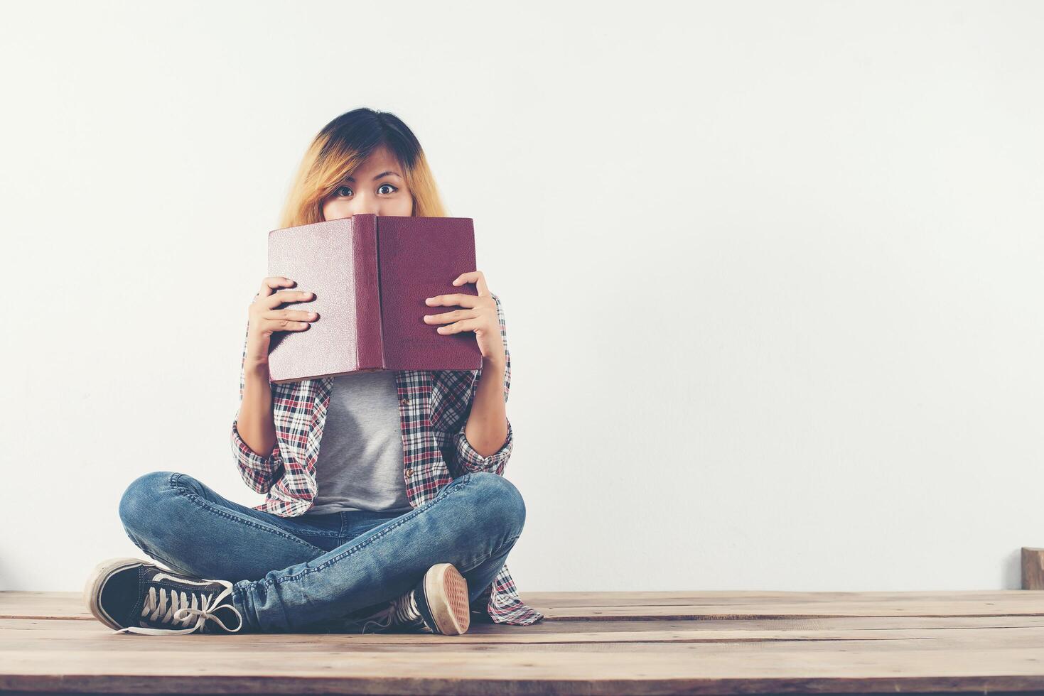 giovane donna hipster si tolse il libro dalla faccia con timidezza. foto