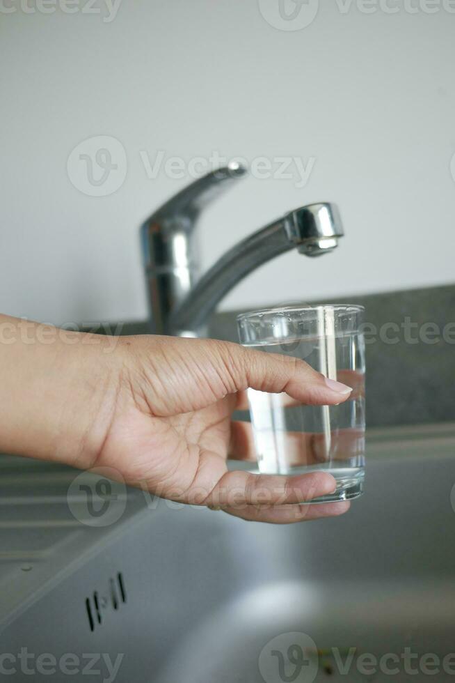 acqua scrosciante a partire dal un' rubinetto rubinetto nel un' bicchiere, potabile puro acqua concetto foto