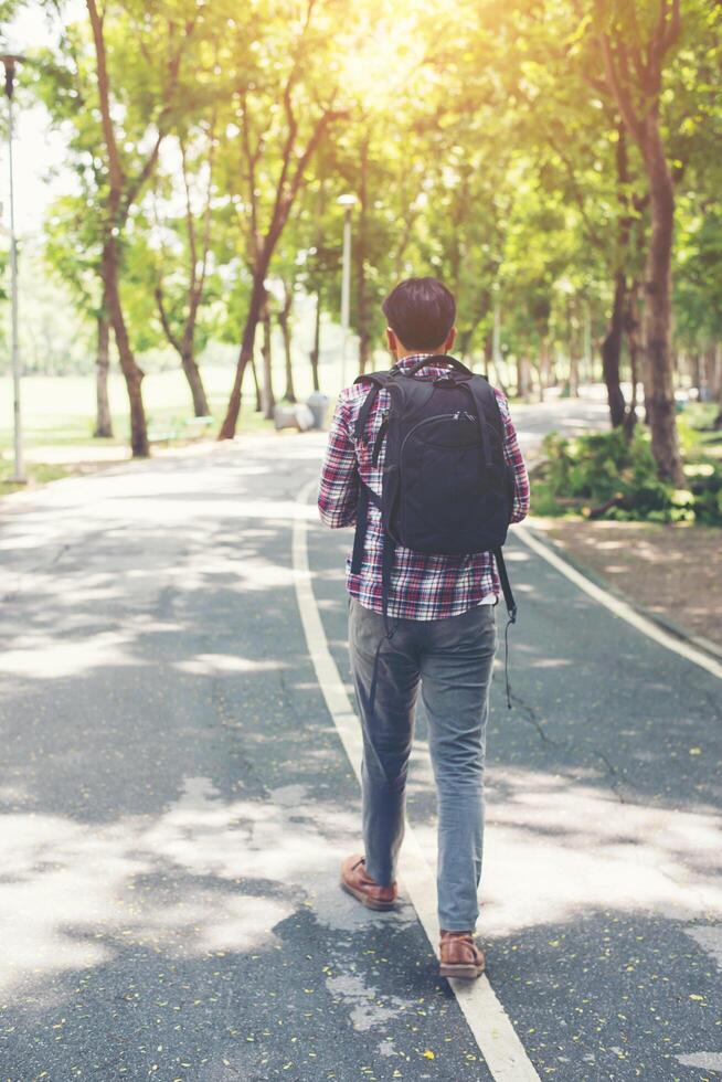 uomo con zaino che cammina sulla strada laterale foto