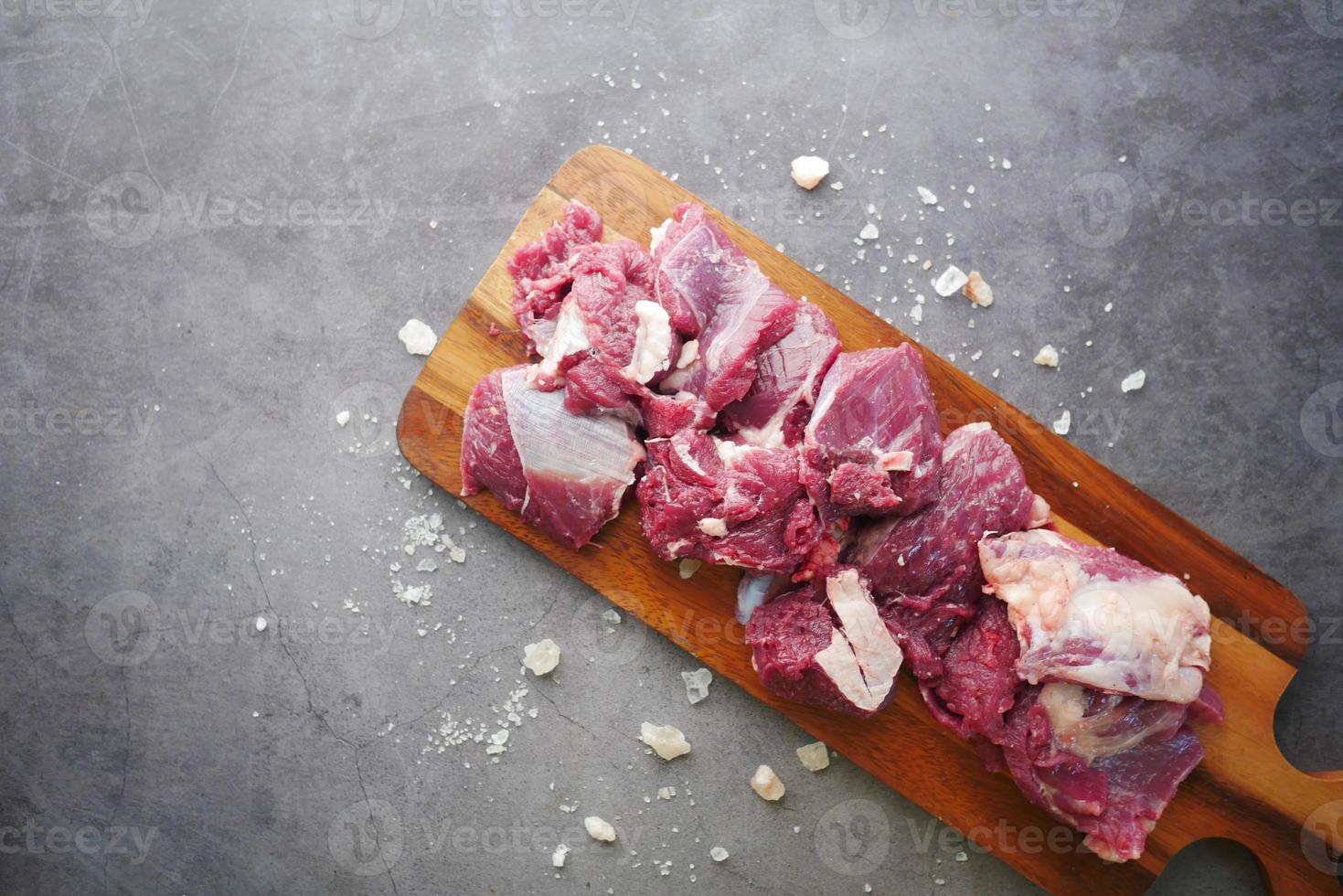 carne cruda e salgemma sul tagliere su sfondo nero foto