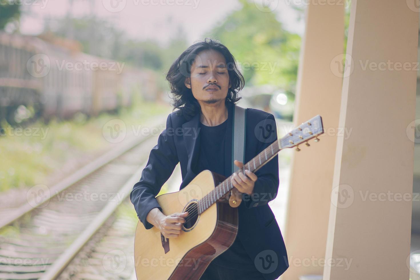 uomo che suona la chitarra all'aperto sui binari della ferrovia foto