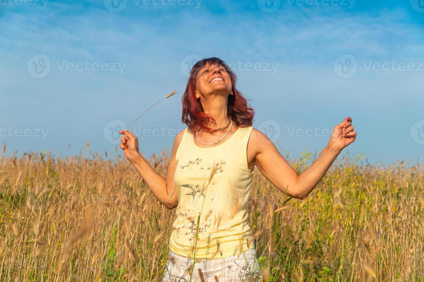 donna sorridente nel campo estivo al tramonto, concetto di positività foto