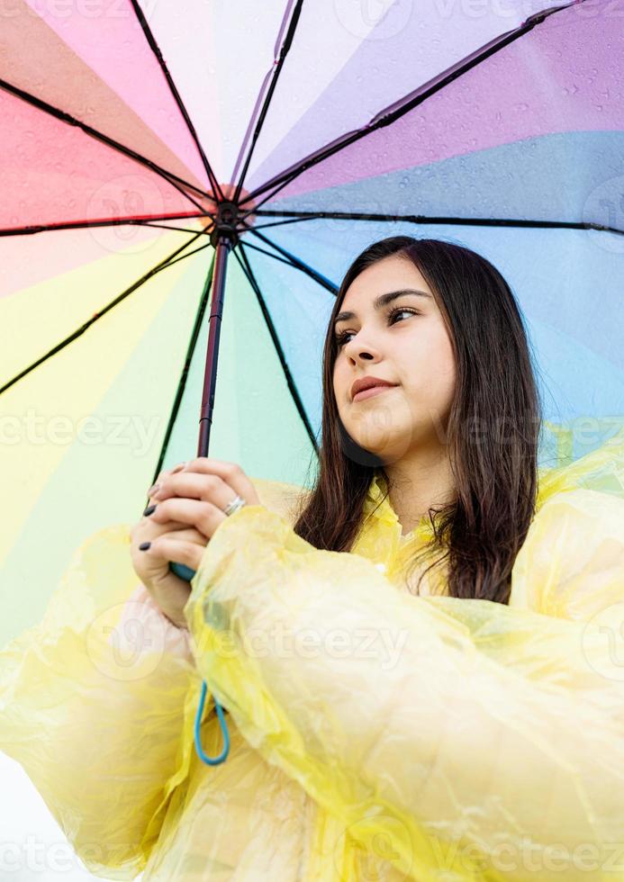 bella donna bruna con ombrello colorato fuori sotto la pioggia foto