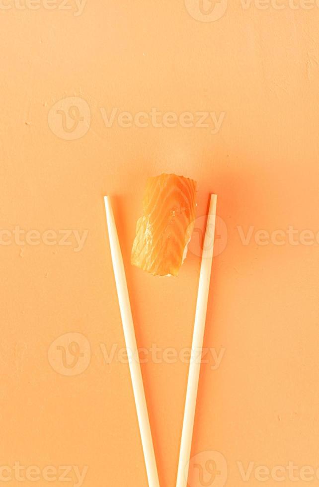 sushi con salmone e bacchette isolate su sfondo arancione foto