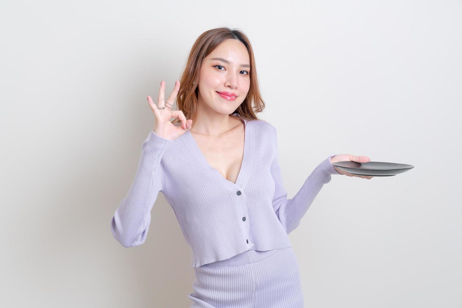 ritratto bella donna asiatica che tiene piatto vuoto su sfondo bianco foto