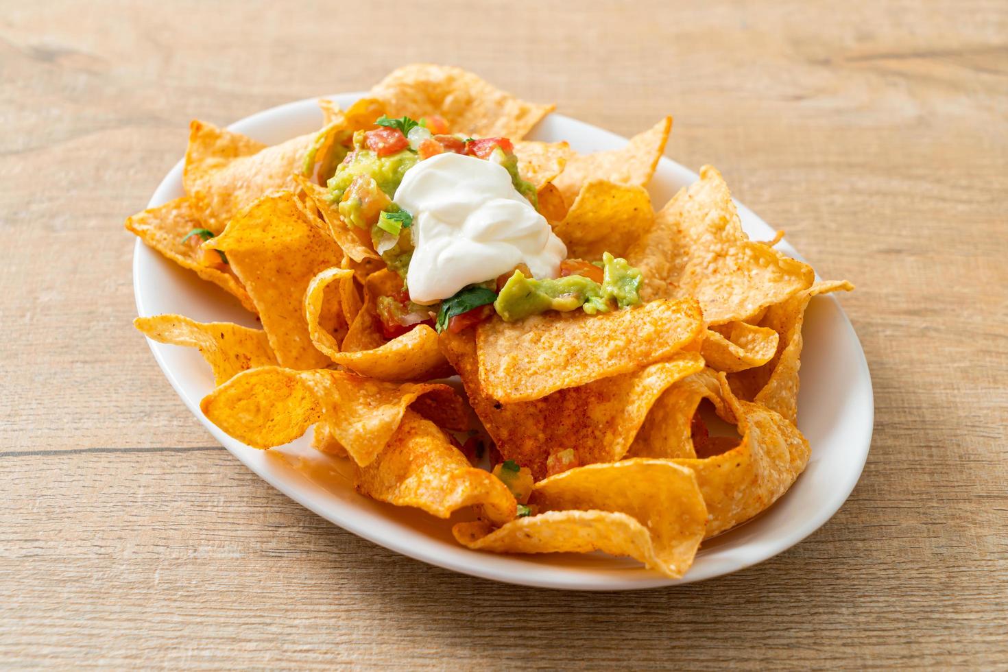 tortilla chips di nachos messicani con jalapeno, guacamole, salsa di pomodori e dip foto