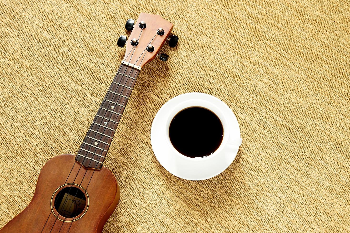 vista dall'alto con ukulele sul pavimento ci sono una tazza di caffè è posizionata foto
