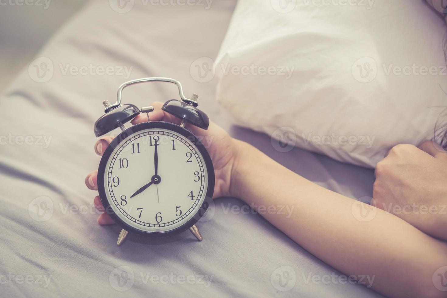 le mani del primo piano della donna spengono la sveglia nel buongiorno. foto