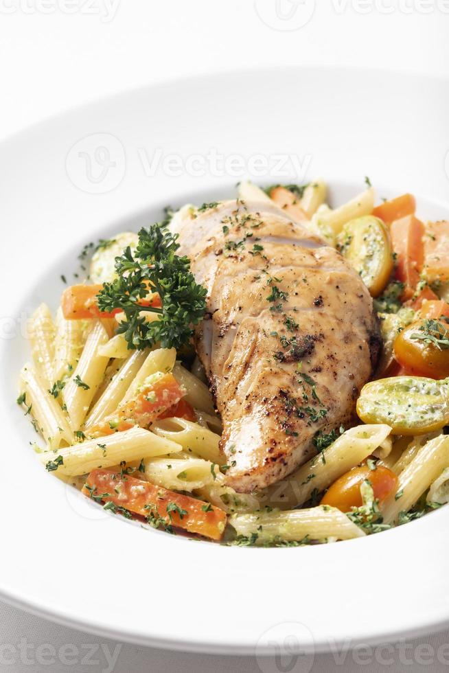 petto di pollo fritto con penne e verdure saltate piatto di pasta su sfondo bianco foto