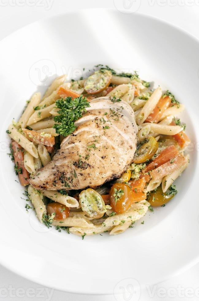 petto di pollo fritto con penne e verdure saltate piatto di pasta su sfondo bianco foto