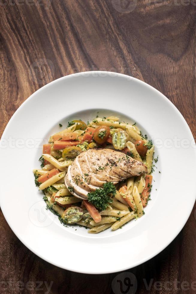 petto di pollo fritto con penne e verdure saltate piatto di pasta su sfondo bianco foto
