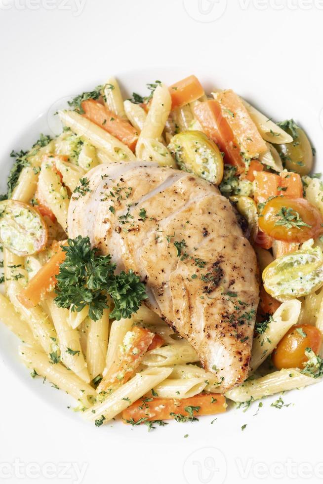 petto di pollo fritto con penne e verdure saltate piatto di pasta su sfondo bianco foto