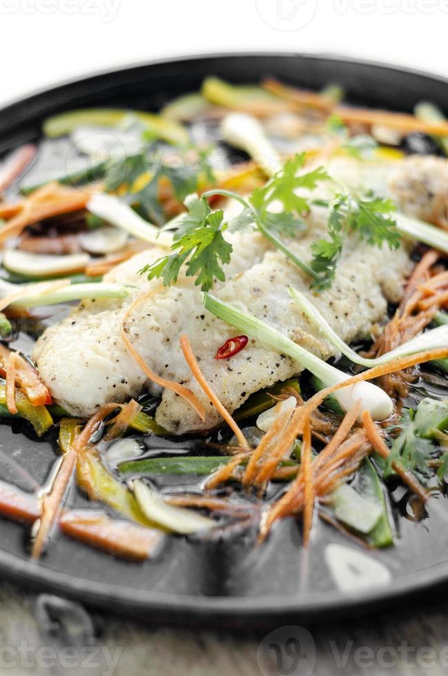 Filetto di pesce piccante al vapore in stile cantonese cinese con verdure su piastra calda foto