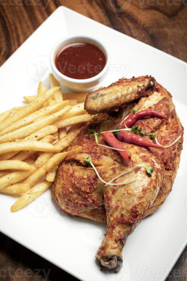 Piri piri portoghese piccante mezzo pollo arrosto con patatine fritte sulla piastra nel ristorante di Lisbona foto