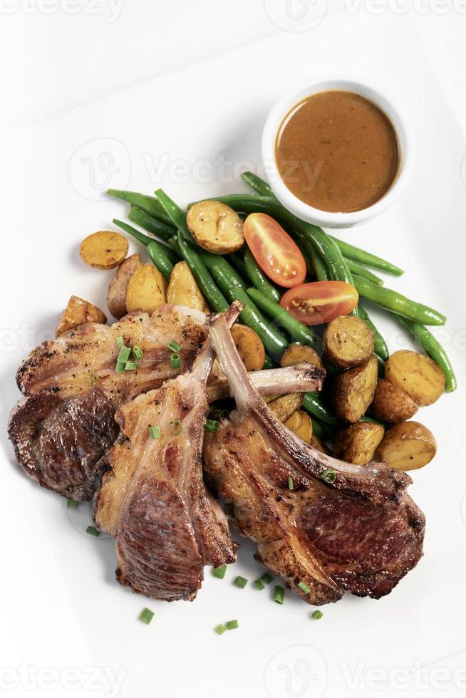 Costolette di agnello organiche australiane con verdure e farina di sugo su sfondo bianco foto