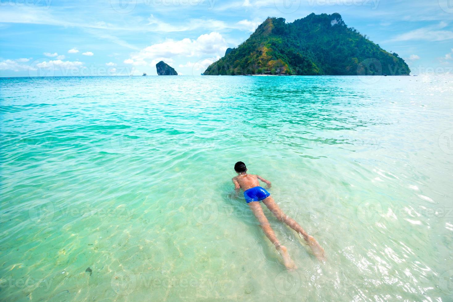 giovane ragazzo nuota e rilassati nel limpido mare tropicale foto